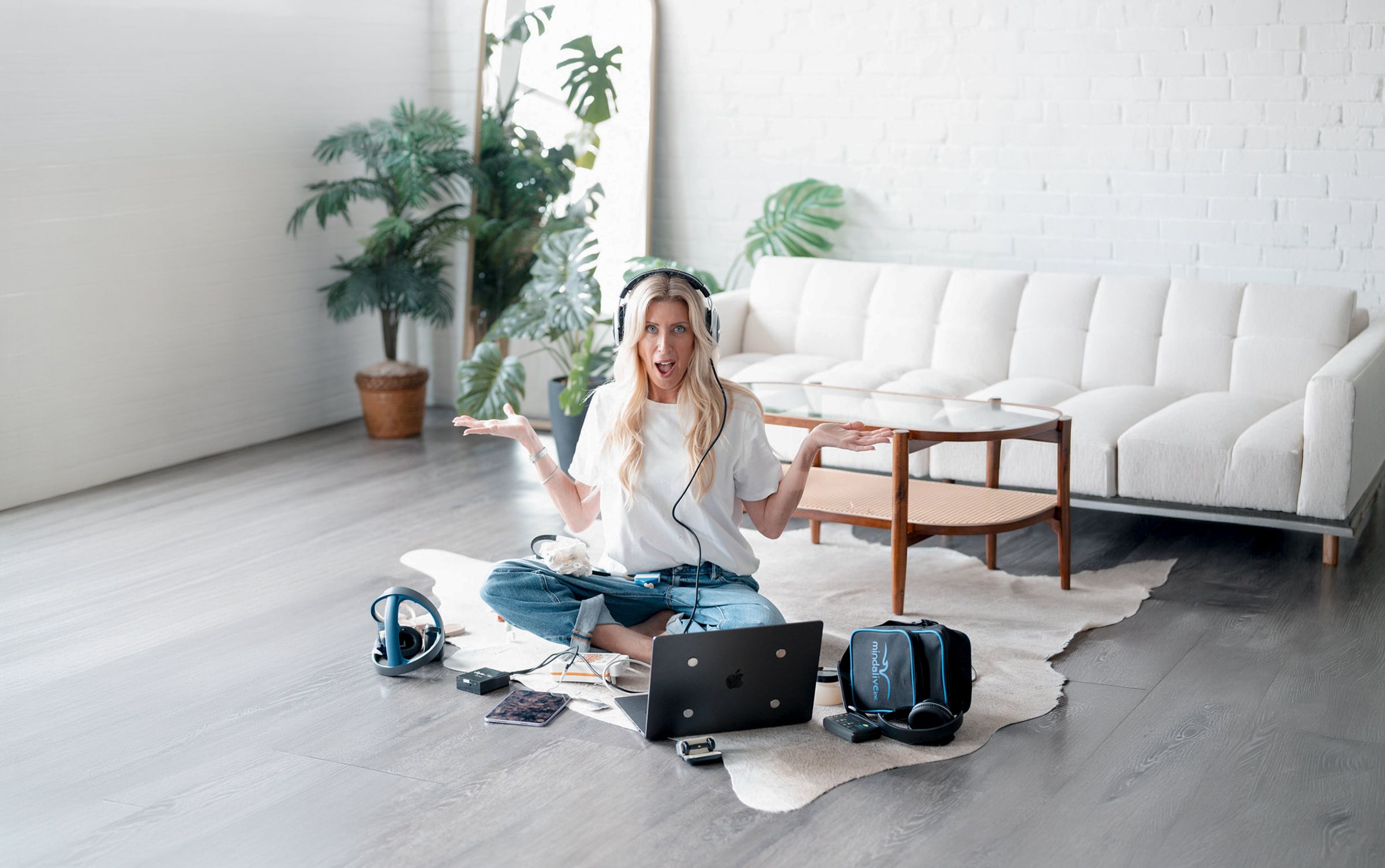 Erin Badour sitting on a rug wearing neurofeedback headphones, surrounded by a laptop and brain-training equipment